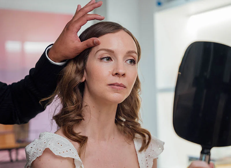 Woman looking in a mirror, with Dr.Sitapara's hand lifting her eyebrow - Hair in Bethesda, MD